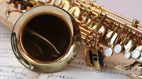 A detailed view of a saxophone resting on sheet music, highlighting its brass finish.