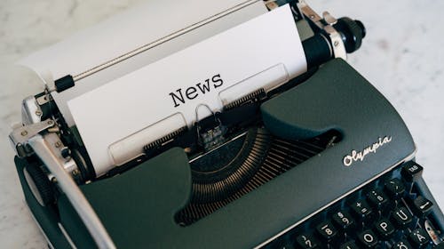 Close-up of an antique typewriter with 'News' on paper.